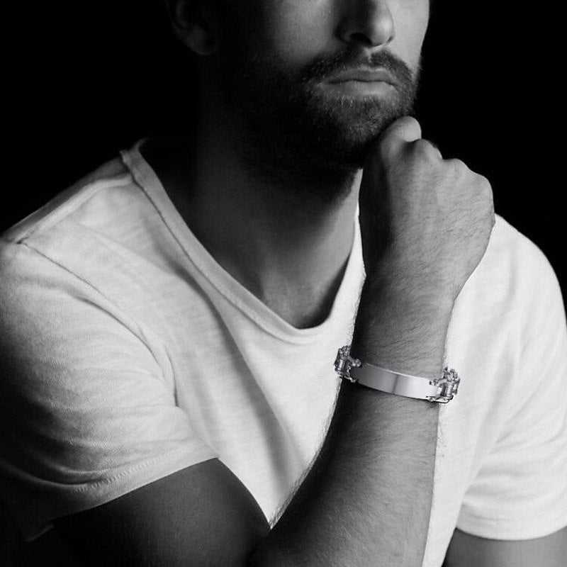 Man wearing a silver bracelet on his wrist with a black background