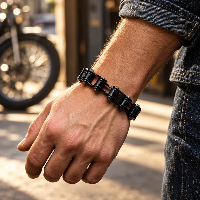 Black bike-chain bracelet worn with a dark denim shirt in a sunlit workshop setting